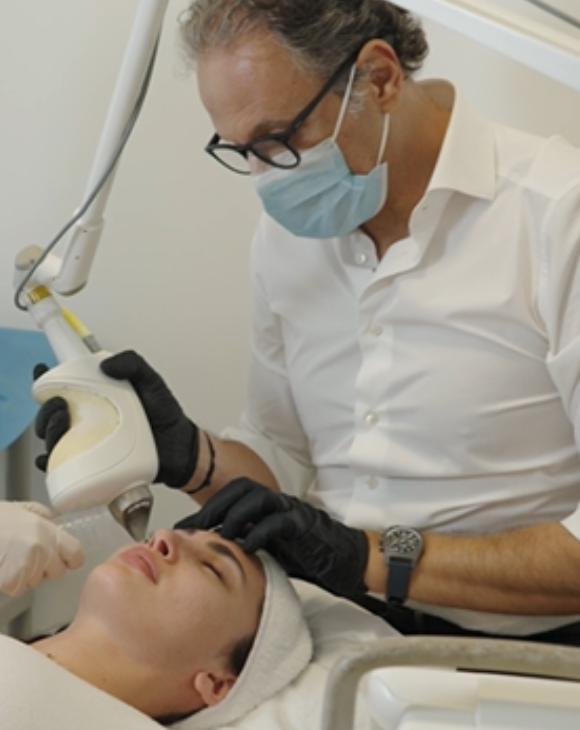 Dr. Dany Touma performing a laser treatment on a female patient for dark circles